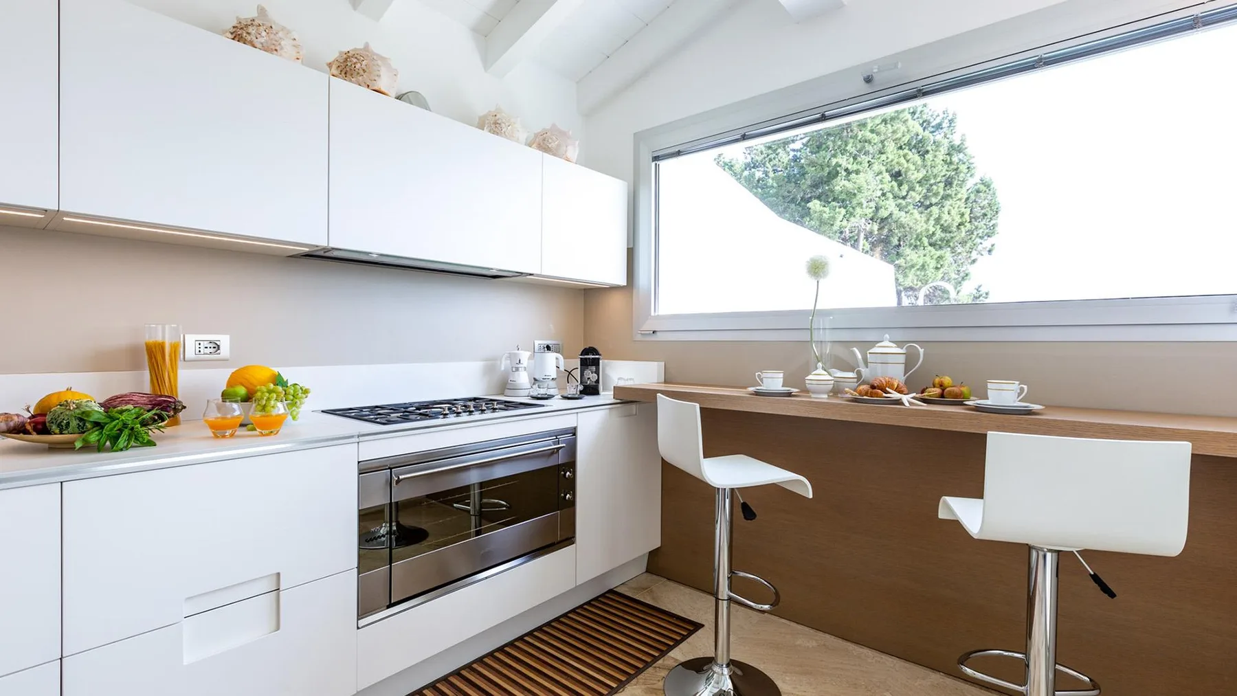 Una cocina luminosa con gabinetes blancos, una estufa y una barra junto a la ventana.