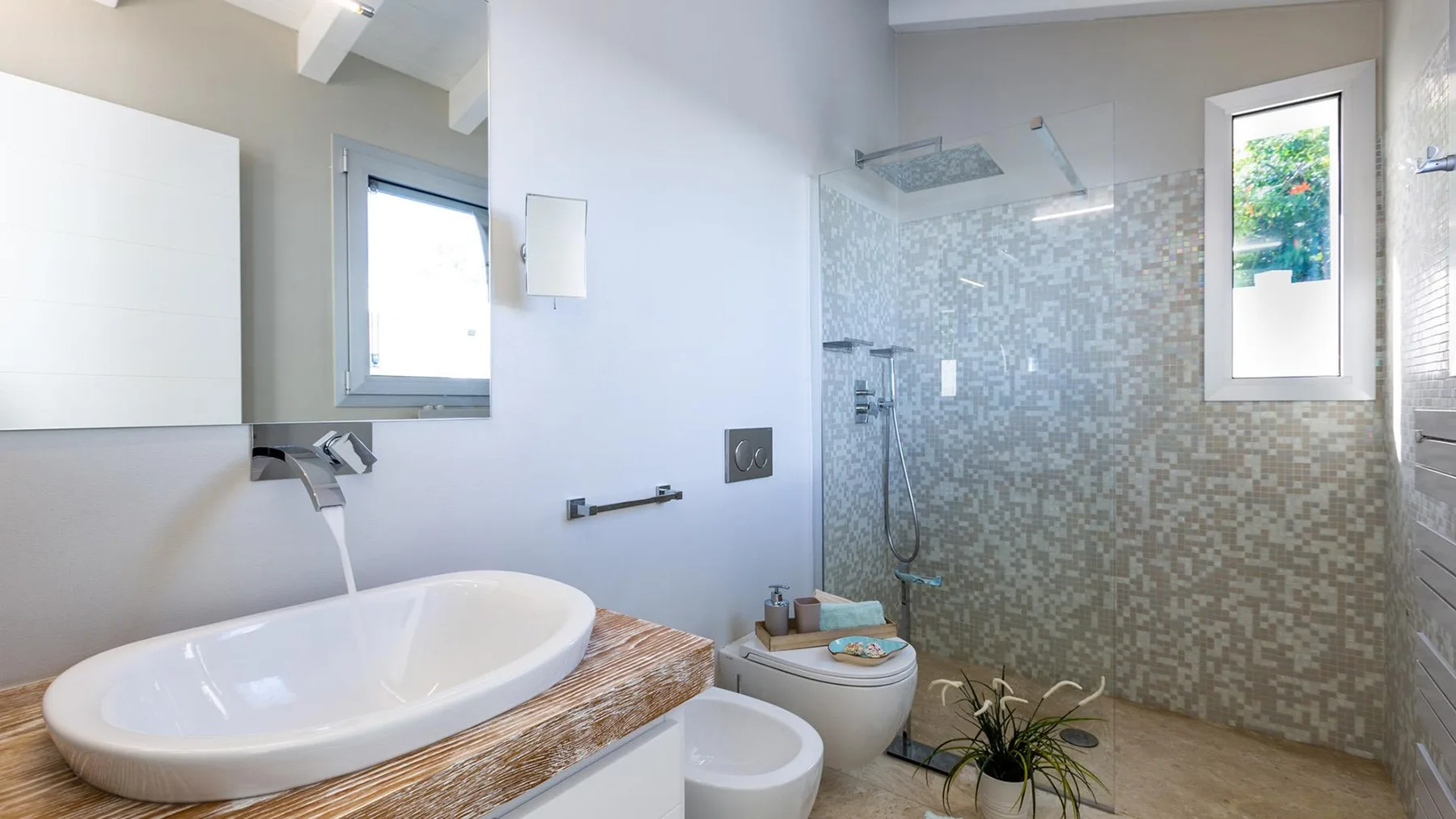 Un baño luminoso con lavabo sobre encimera y ducha con mampara de vidrio.