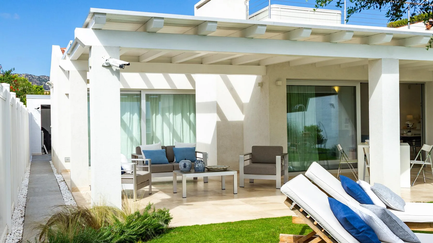 Un patio luminoso con asientos al aire libre y una pérgola cubierta.