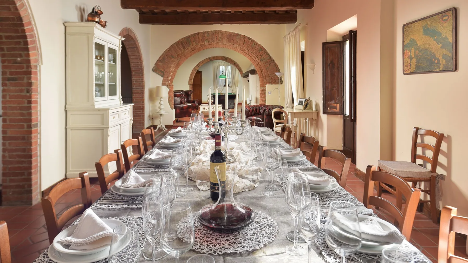 Un comedor con una mesa larga puesta con vajilla bajo arcos de ladrillo.