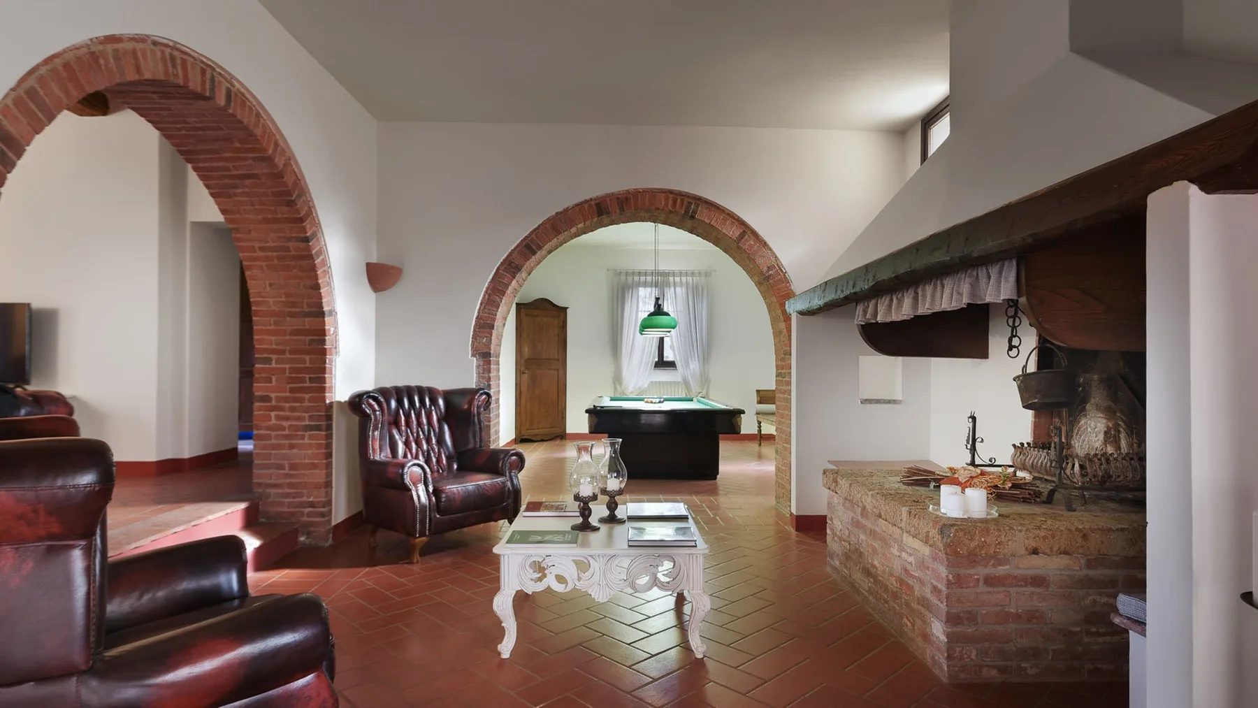 Una sala de estar con arcos de ladrillo, asientos de cuero y una mesa en primer plano.