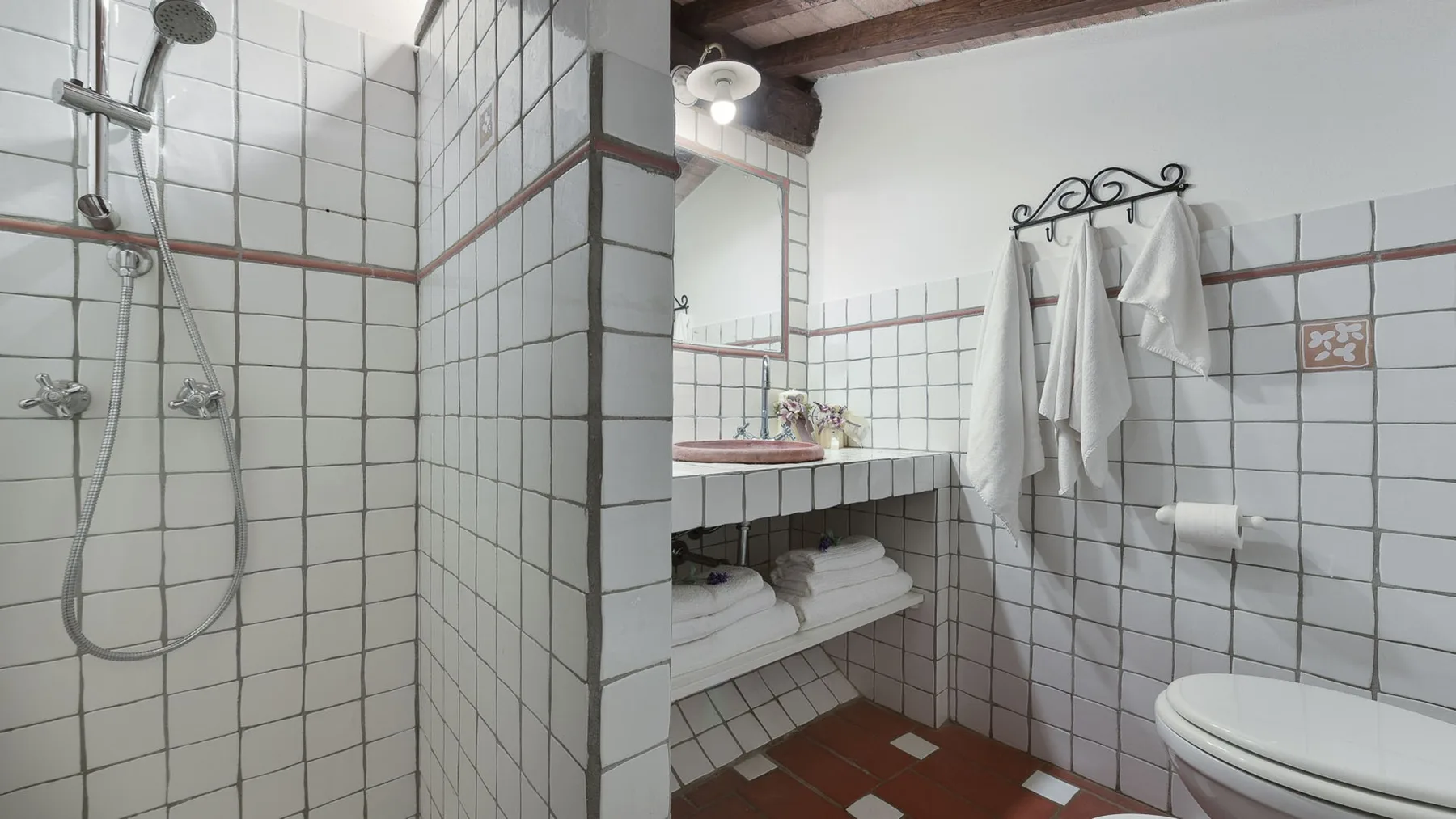 Un baño con azulejos, ducha, lavabo e inodoro.