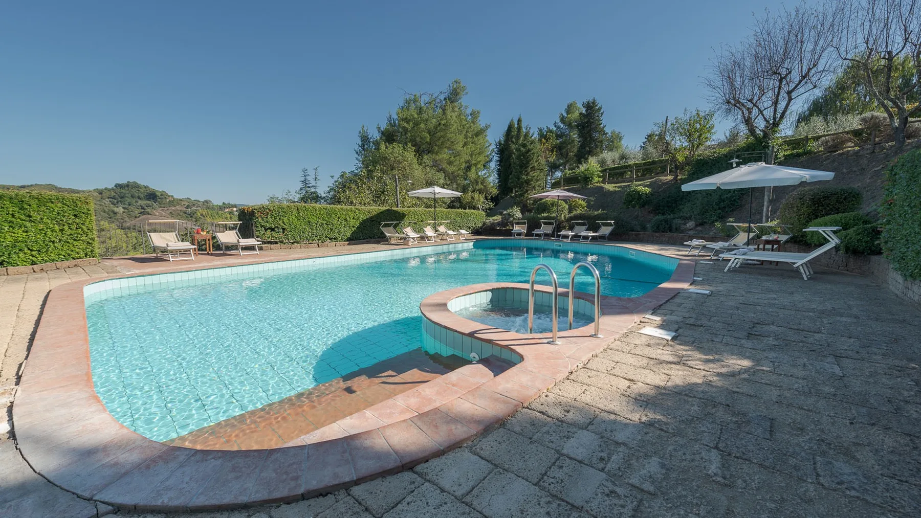 Una piscina al aire libre con un borde curvo y tumbonas cerca.