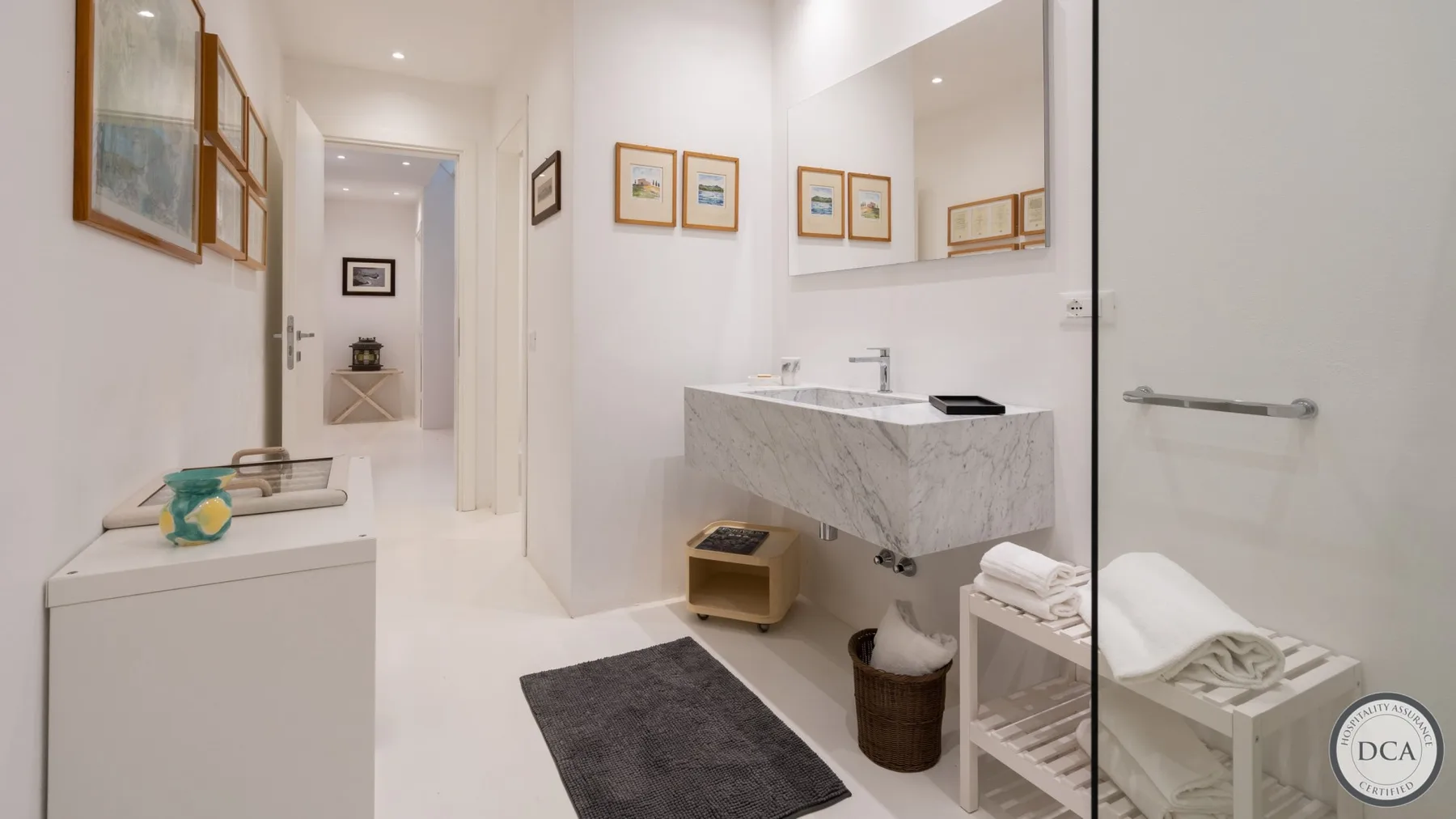 A bright bathroom with a sink, mirror, and dark floor mat.