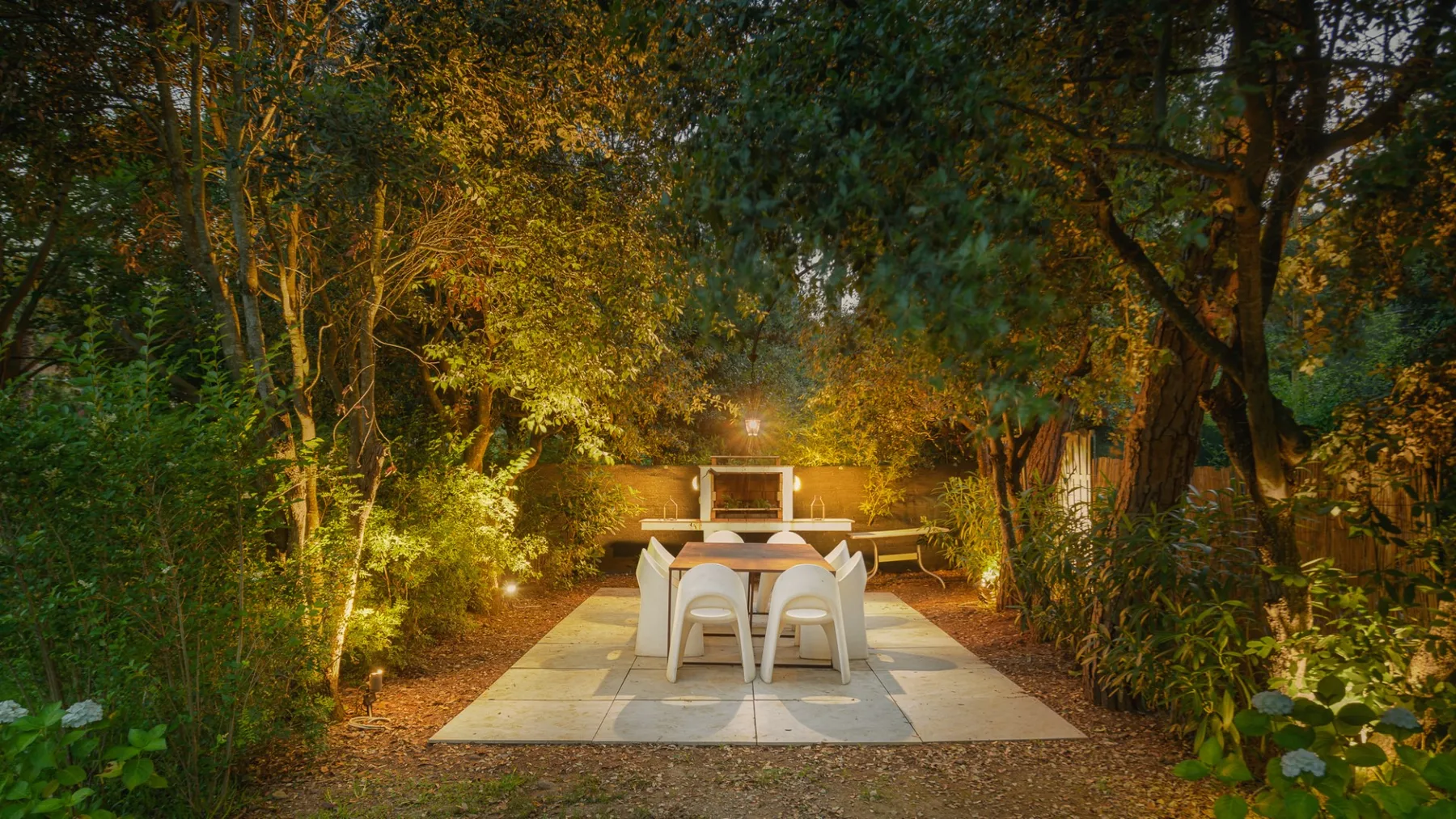 An outdoor dining area with a table and chairs beneath trees.