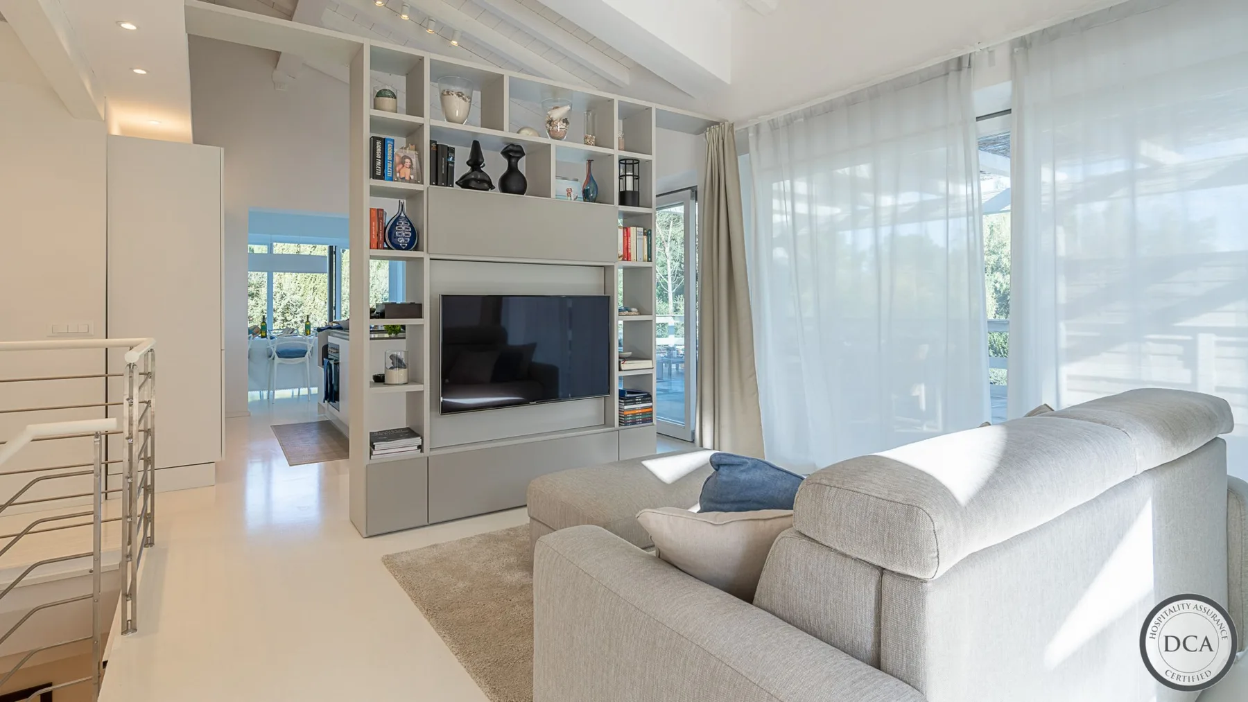 Bright living room with a television set into built-in shelving beside a large window.