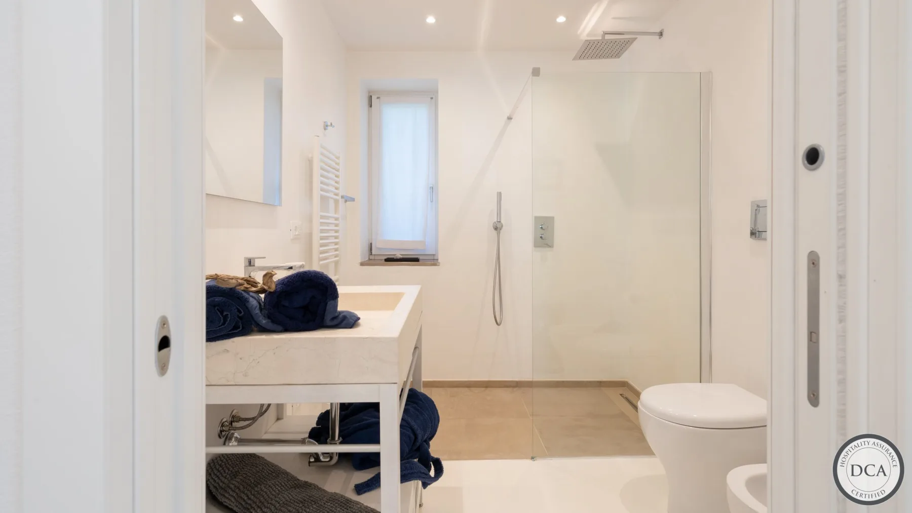 A bright bathroom with a sink, shower, and toilet.