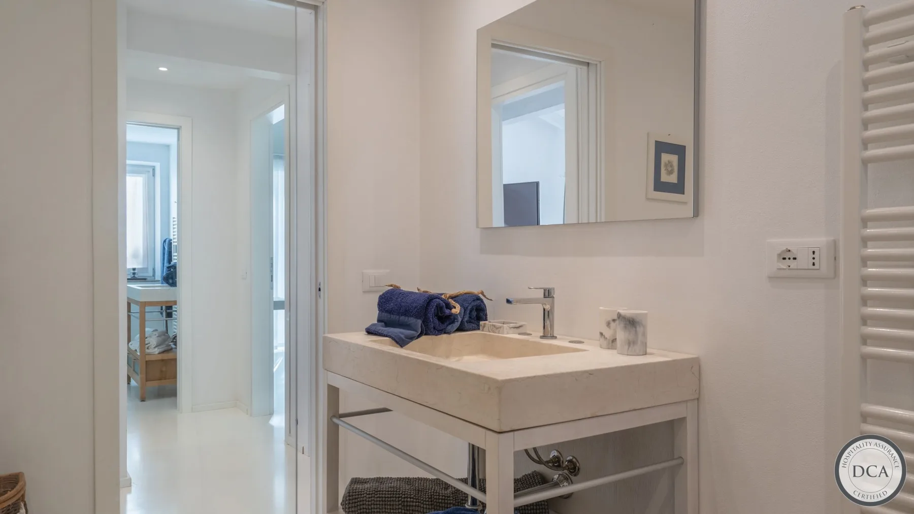 A bathroom vanity with a sink and mirror stands beside an open doorway.