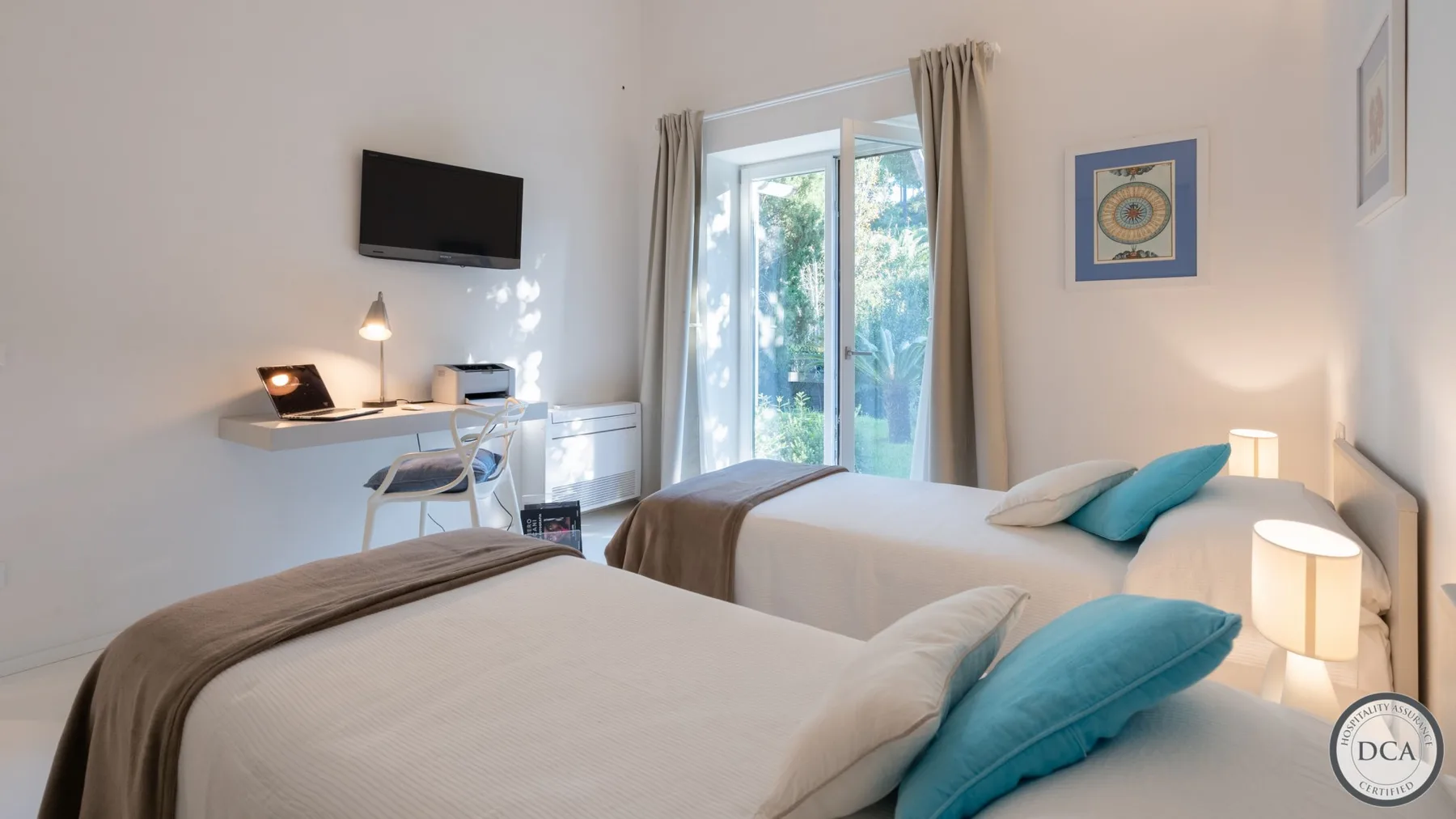 A bright bedroom with two beds and glass doors opening to a balcony.