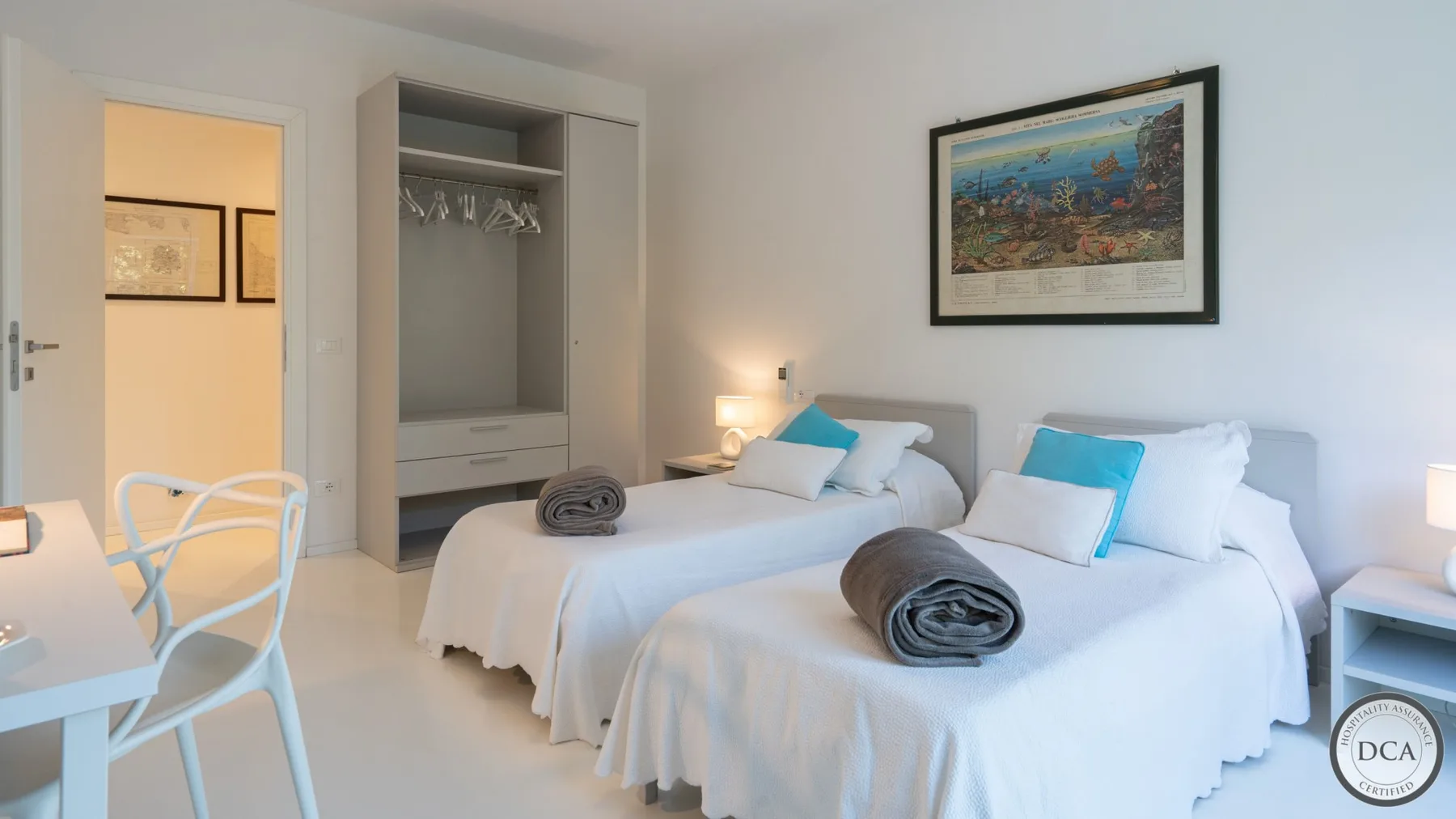 A bedroom with two single beds, white bedding, and an open wardrobe.