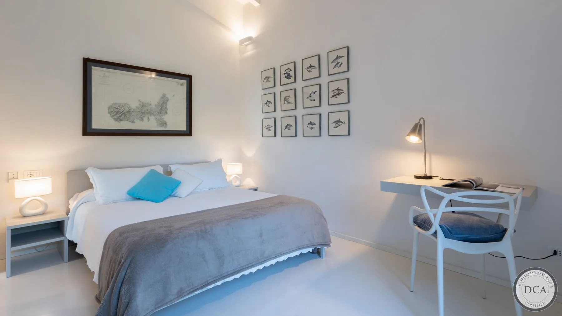A bedroom with a neatly made bed and a desk beside it.