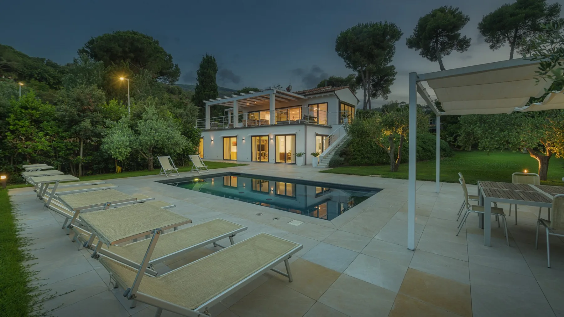 A modern house with a swimming pool and outdoor seating at dusk.