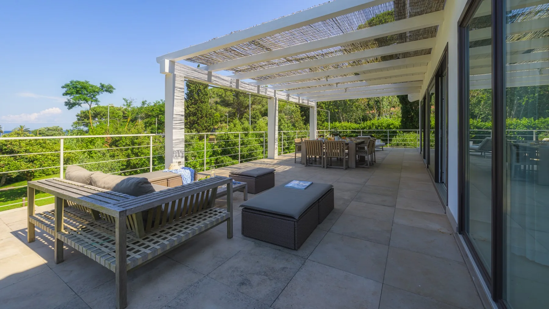 A covered outdoor patio with lounge seating and views of surrounding greenery.