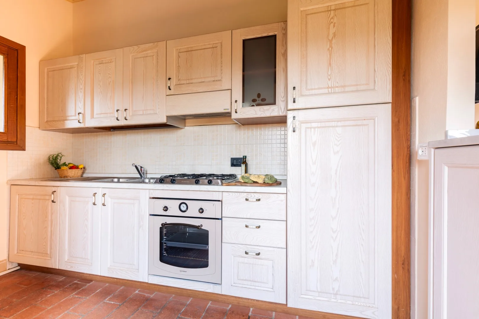 A bright kitchen with light cabinets, a stove, and an oven.