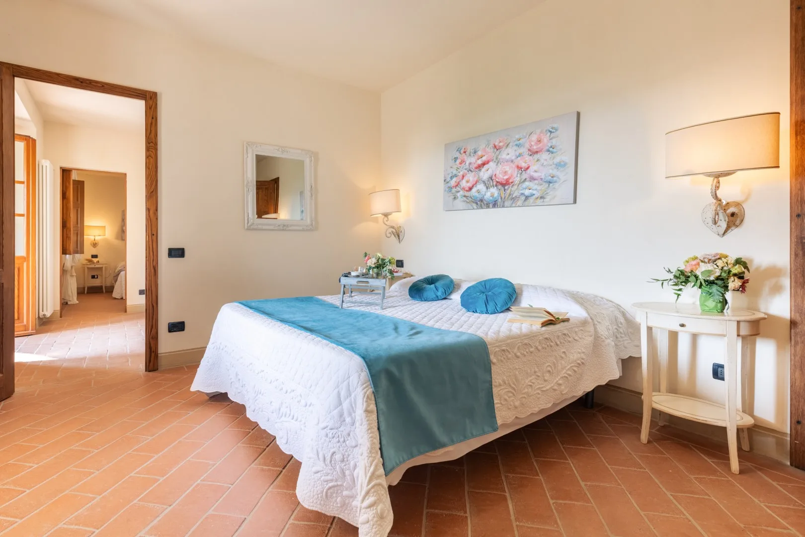 A bedroom with a double bed dressed in white and teal bedding.