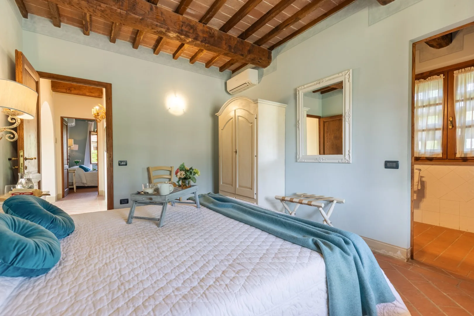 A bedroom with a bed, pale wardrobe, and exposed wooden ceiling beams.