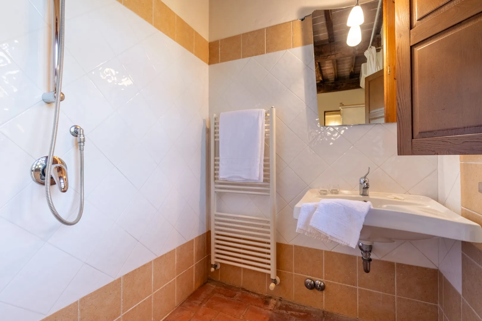 A tiled bathroom with a shower, sink, and towel rack.