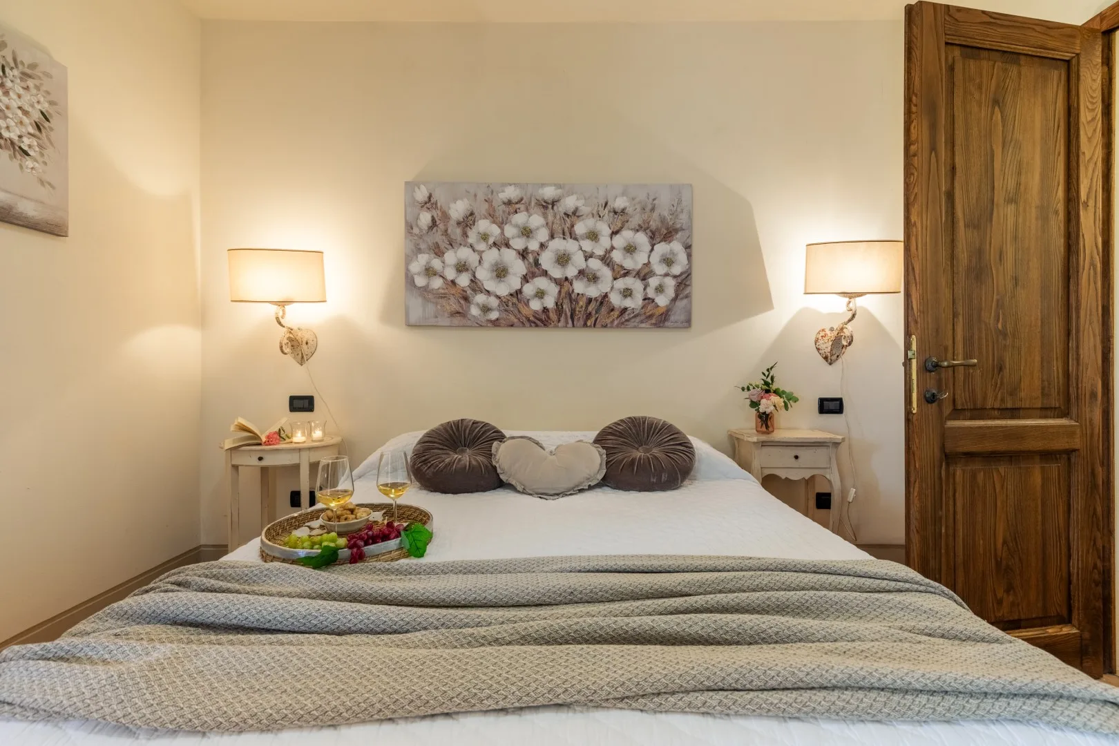 A bedroom with a neatly made bed and floral artwork above it.