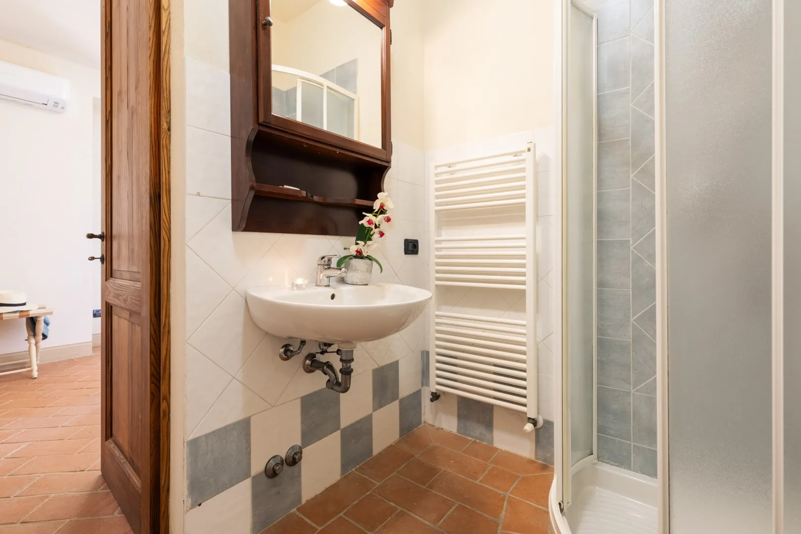 A bathroom with a wall-mounted sink, mirror, and shower.