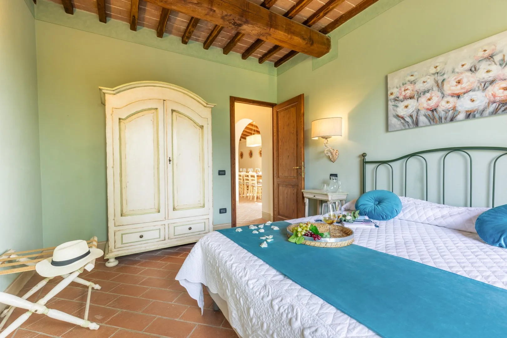 A bedroom with a large bed, a wardrobe, and exposed wooden ceiling beams.