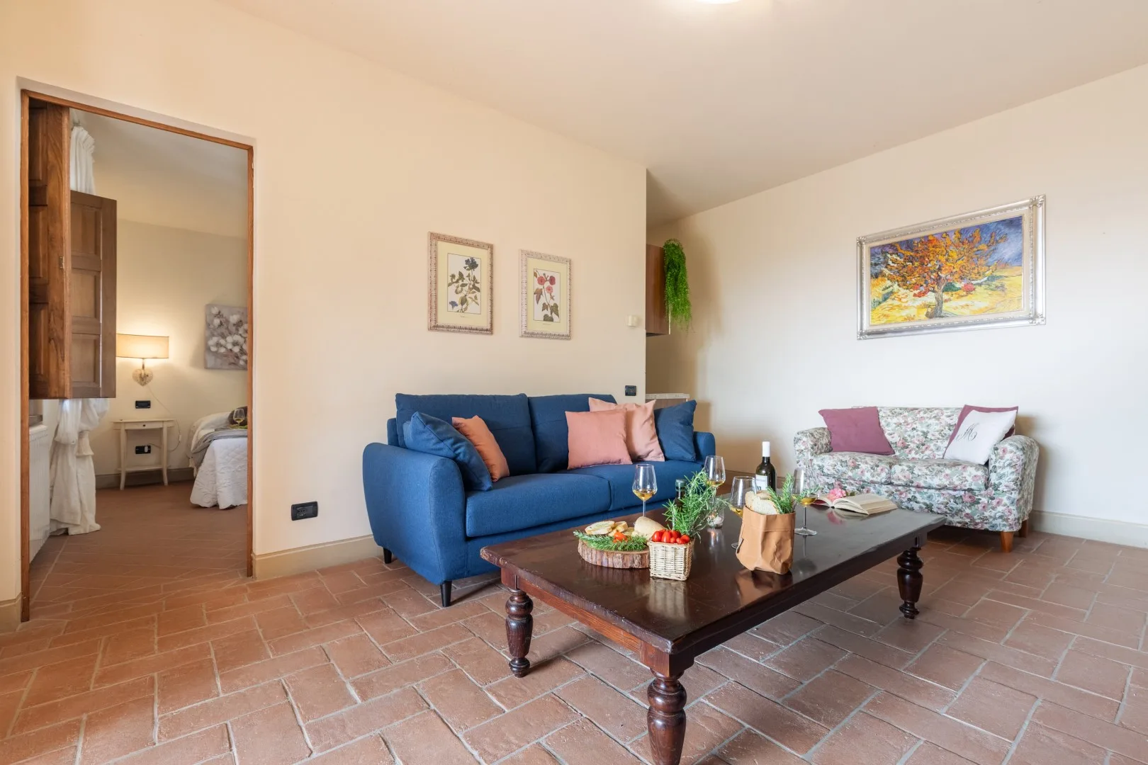 A living room with blue seating, a patterned settee, and a low table.