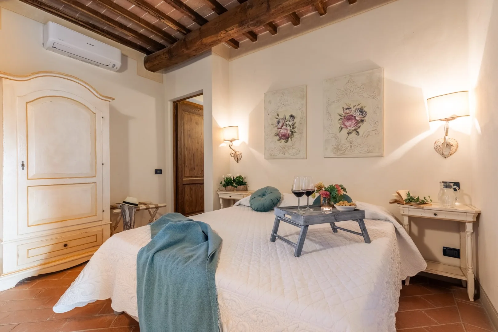 A bedroom with a large bed, wall art, and exposed wooden ceiling beams.