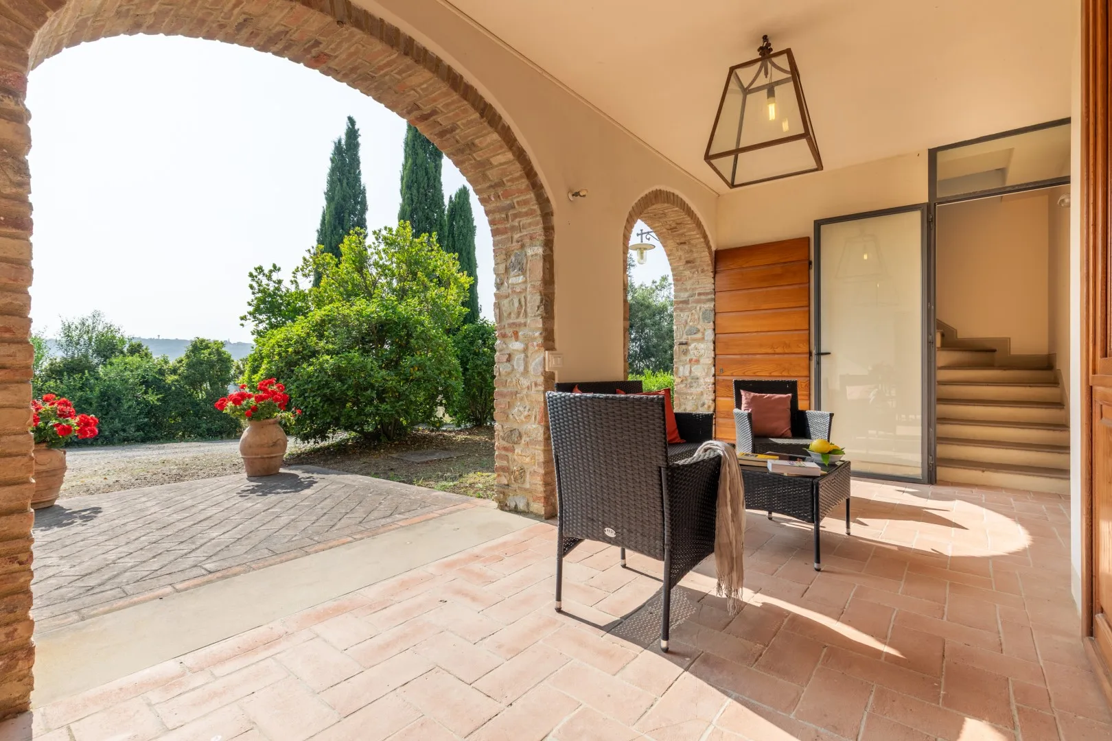 A brick-arched patio with outdoor seating overlooks a garden.