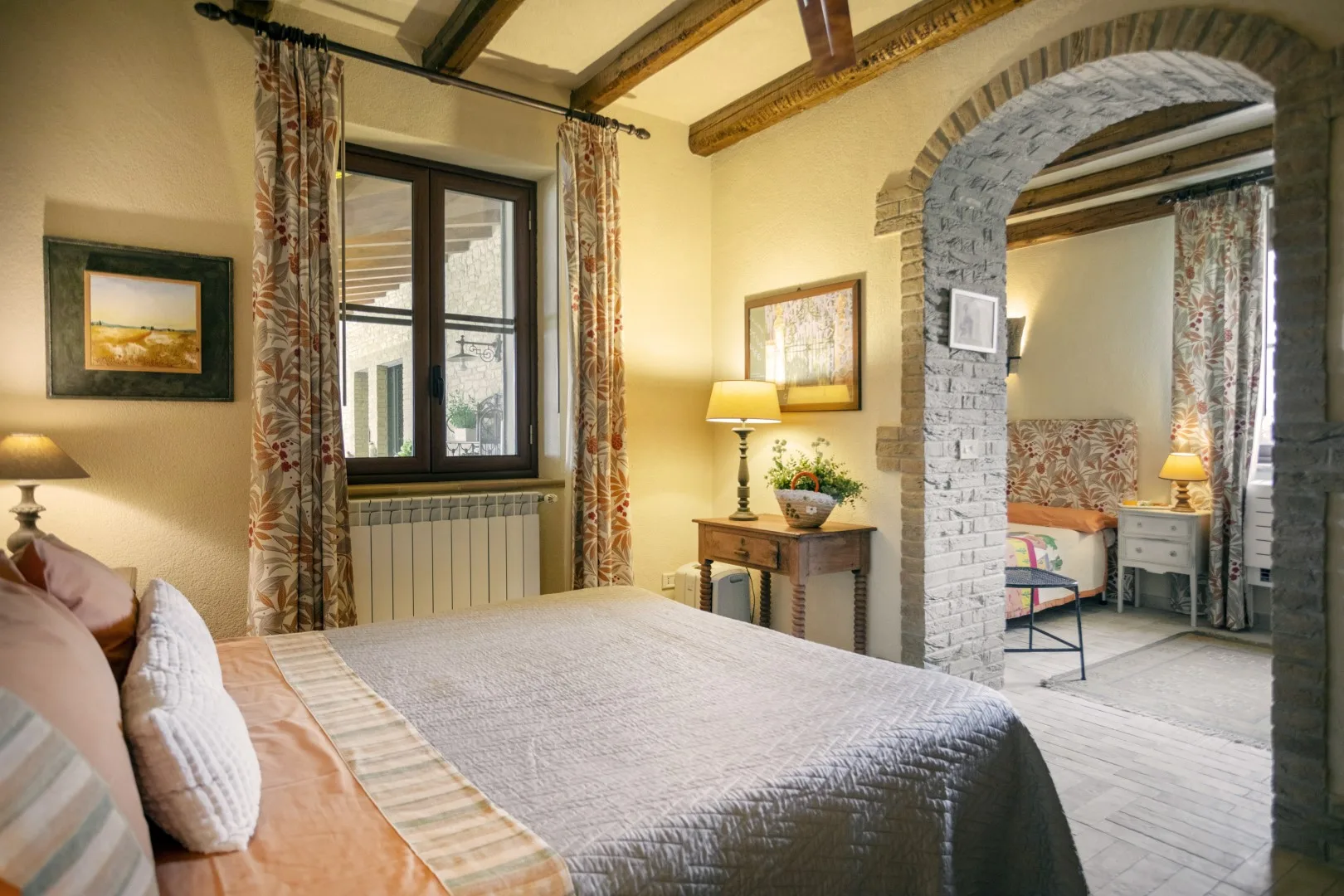 Un dormitorio con una cama grande, una ventana y un arco de piedra.