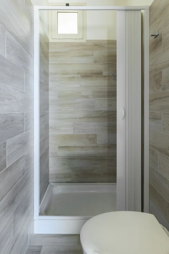 Un baño con azulejos, una ducha cerrada y un inodoro en primer plano.