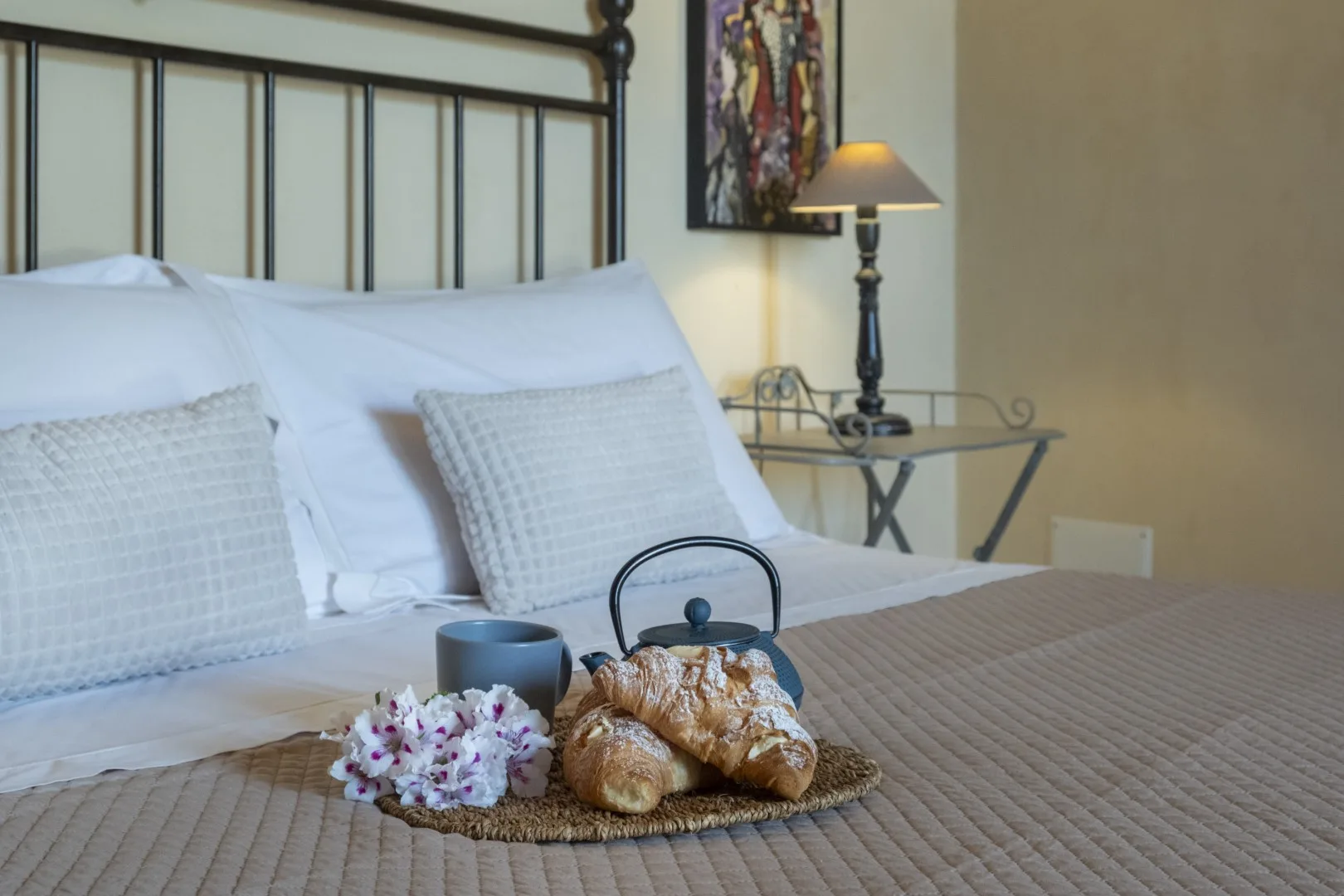 Una cama bien tendida con almohadas blancas y una bandeja de pasteles.