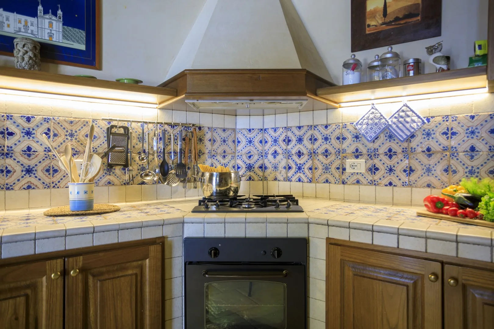 Una cocina con azulejos, gabinetes de madera, una estufa y una campana extractora.