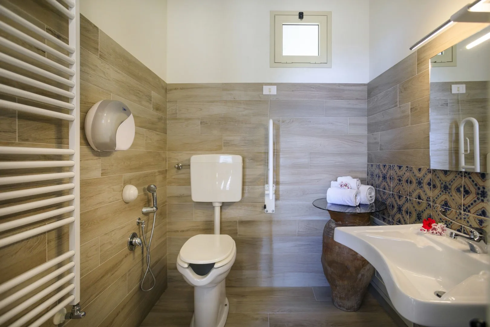 Un baño con azulejos, inodoro, bañera y toallero mural.