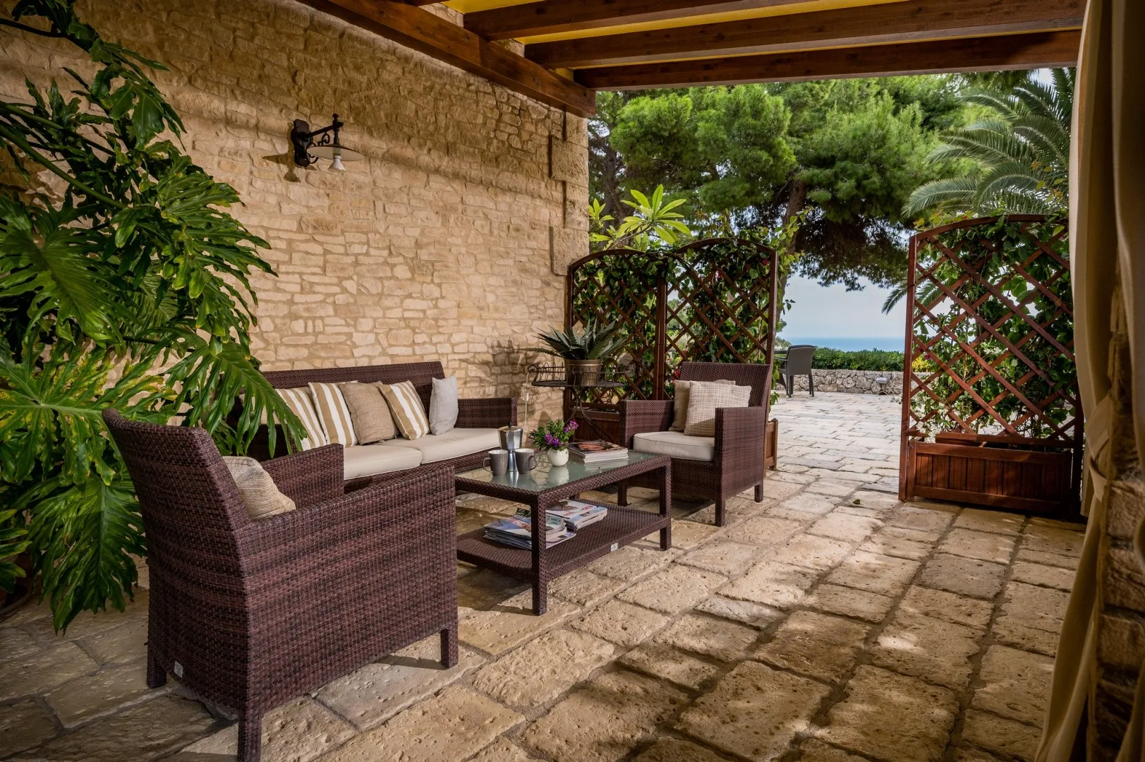 Una zona de estar exterior cubierta con una mesa baja junto a un muro de piedra.