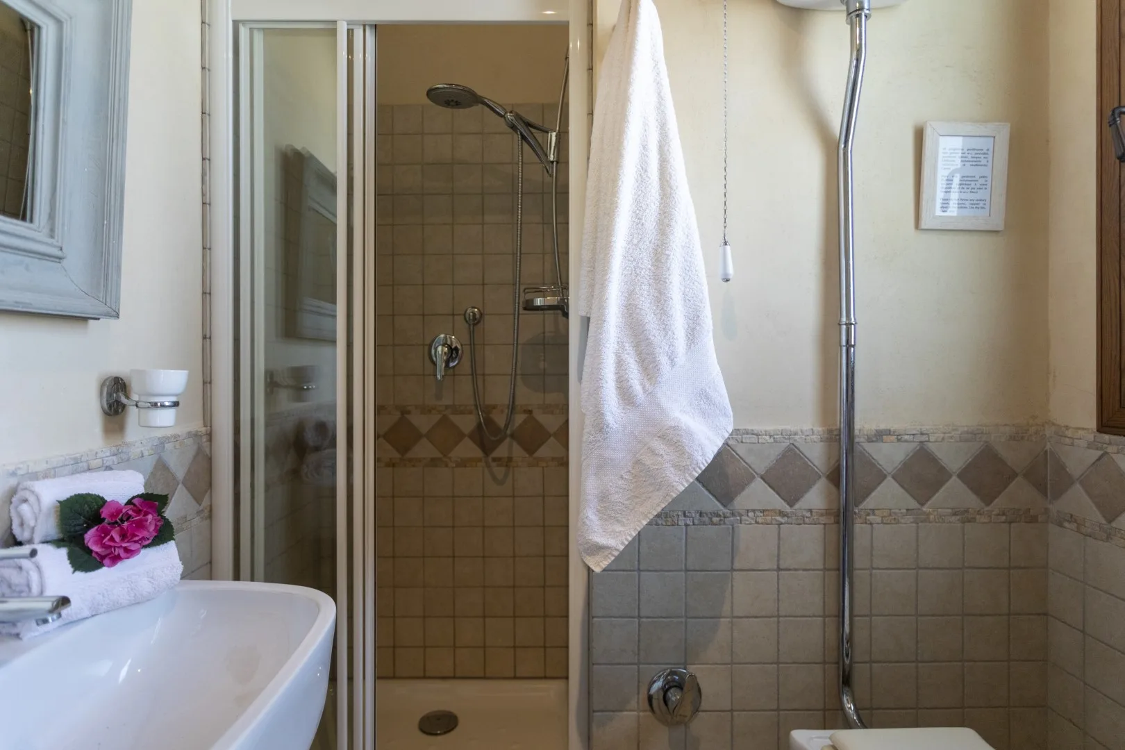 Un baño con ducha de vidrio, paredes alicatadas y un lavabo.