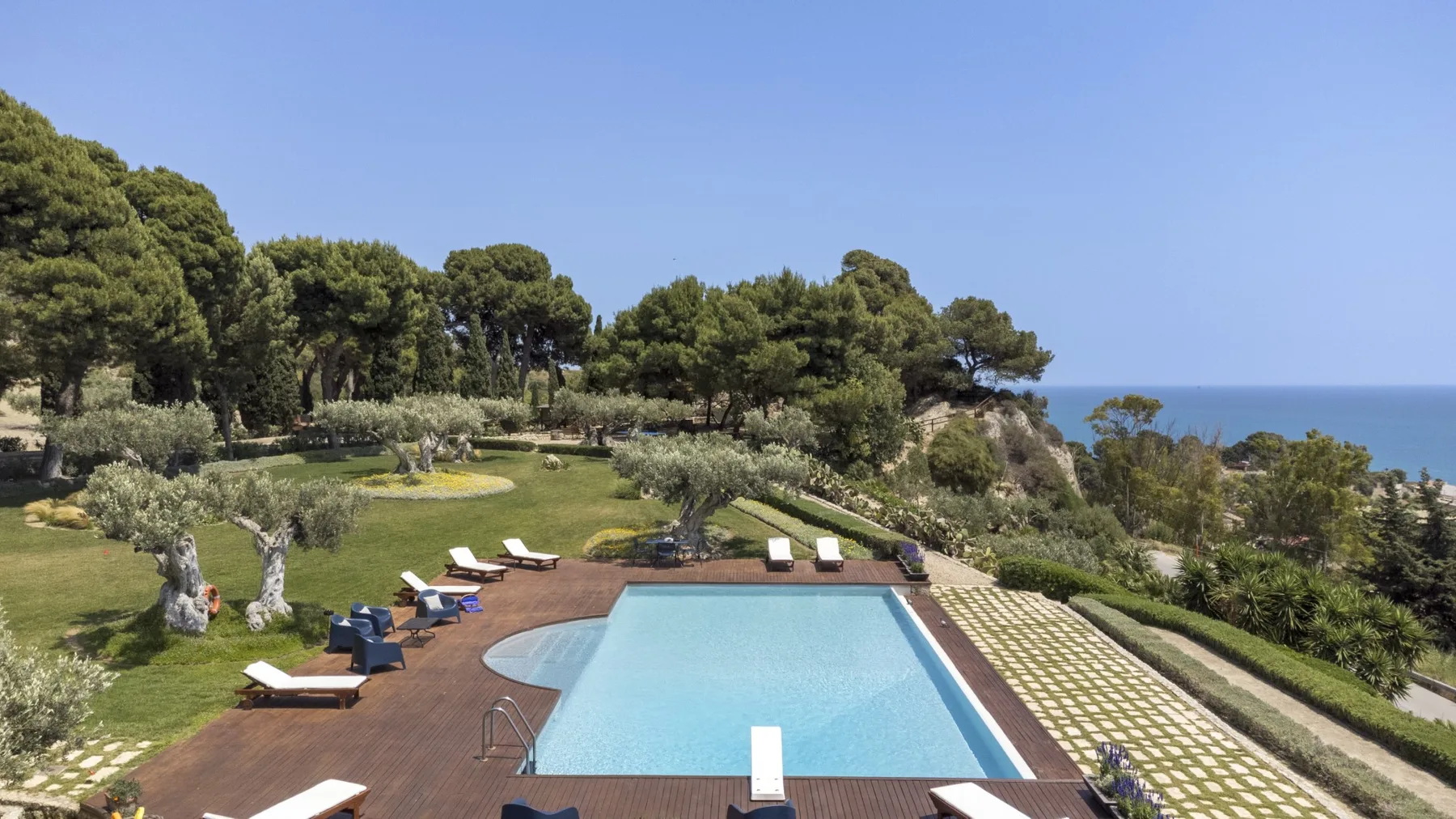 Una piscina y la terraza que la rodea ofrecen vistas a jardines y al mar.