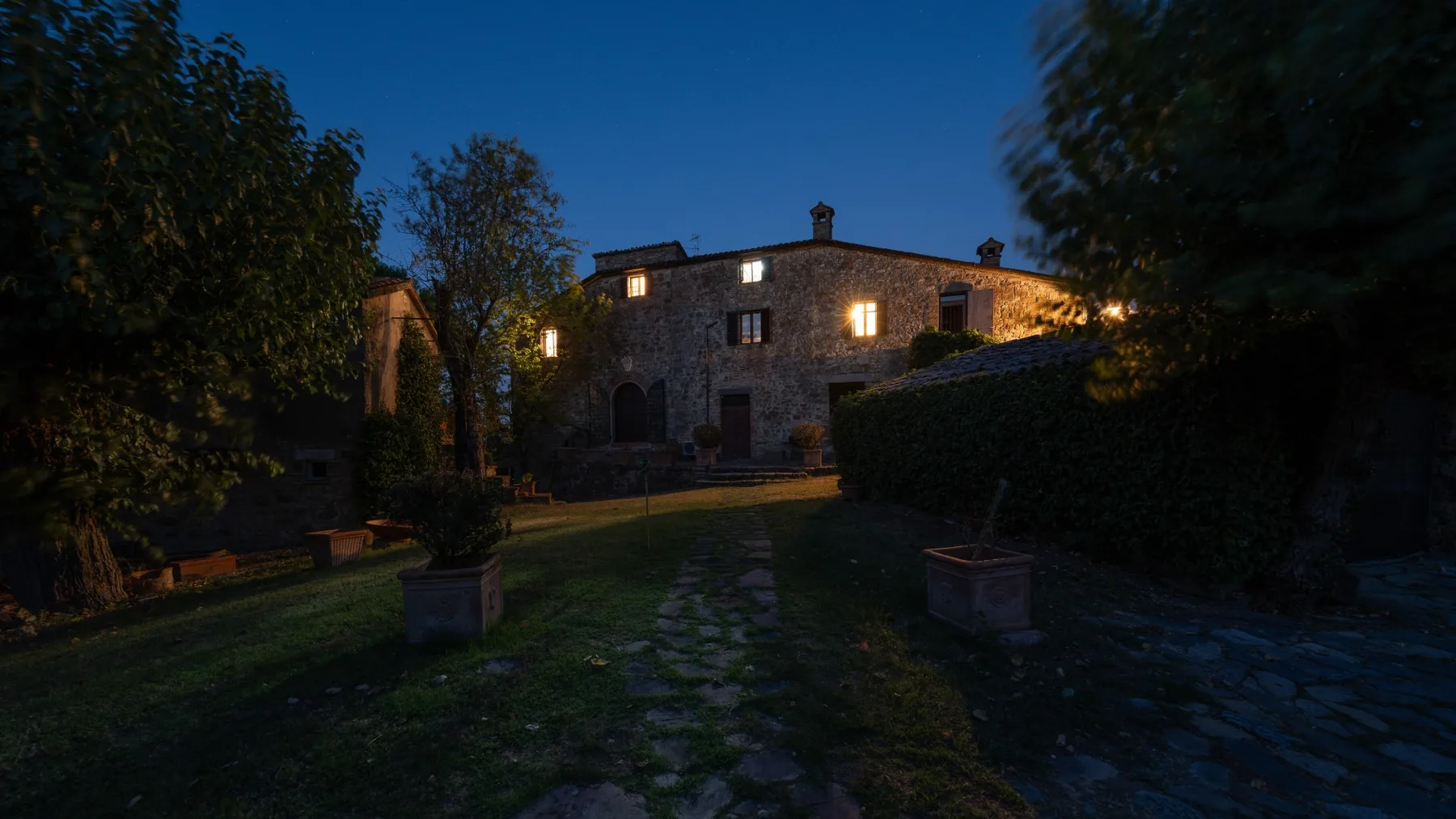 A stone building at dusk, with a path leading through a garden.