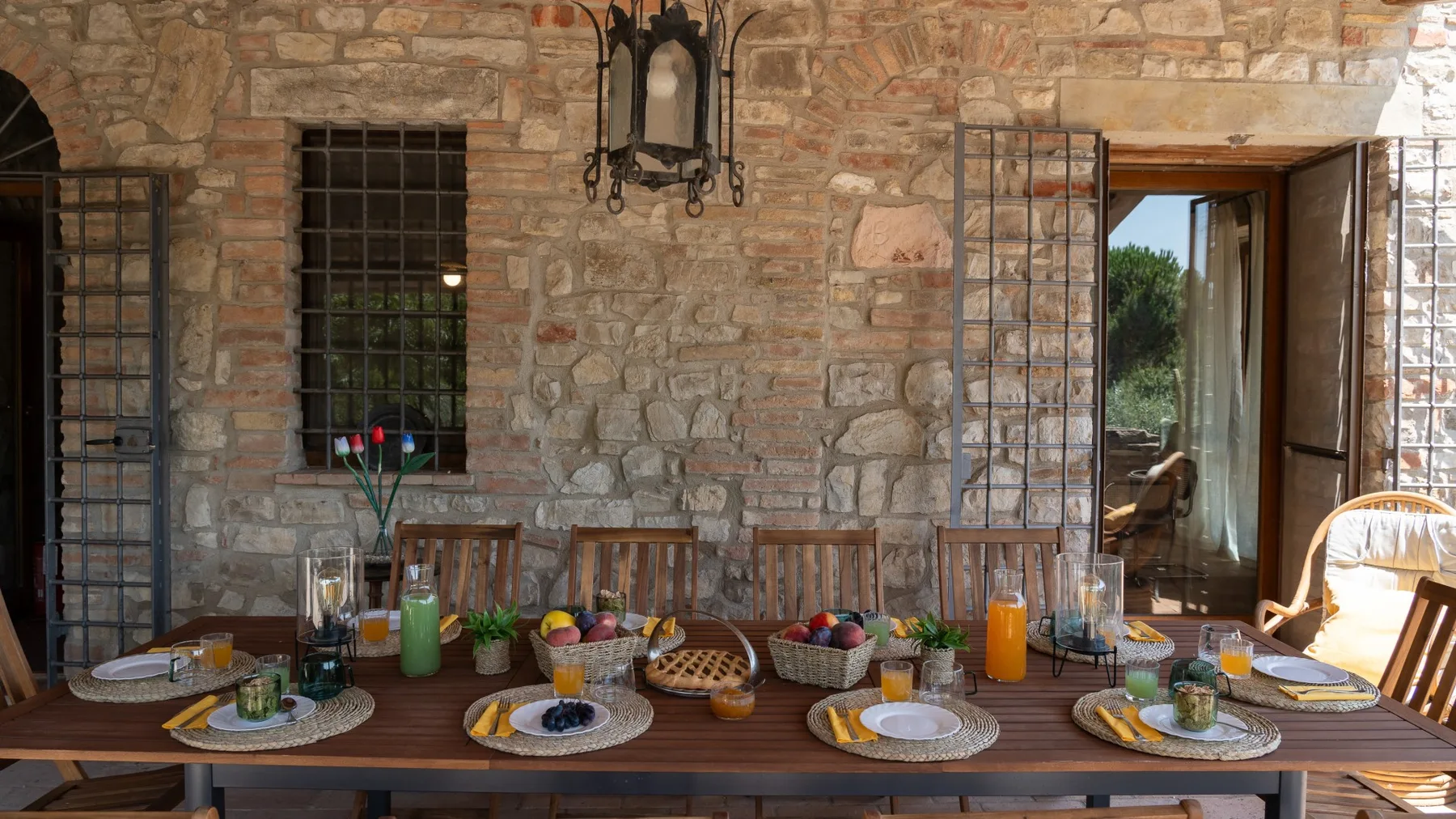 A dining table set with dishes sits in a rustic stone-walled room.