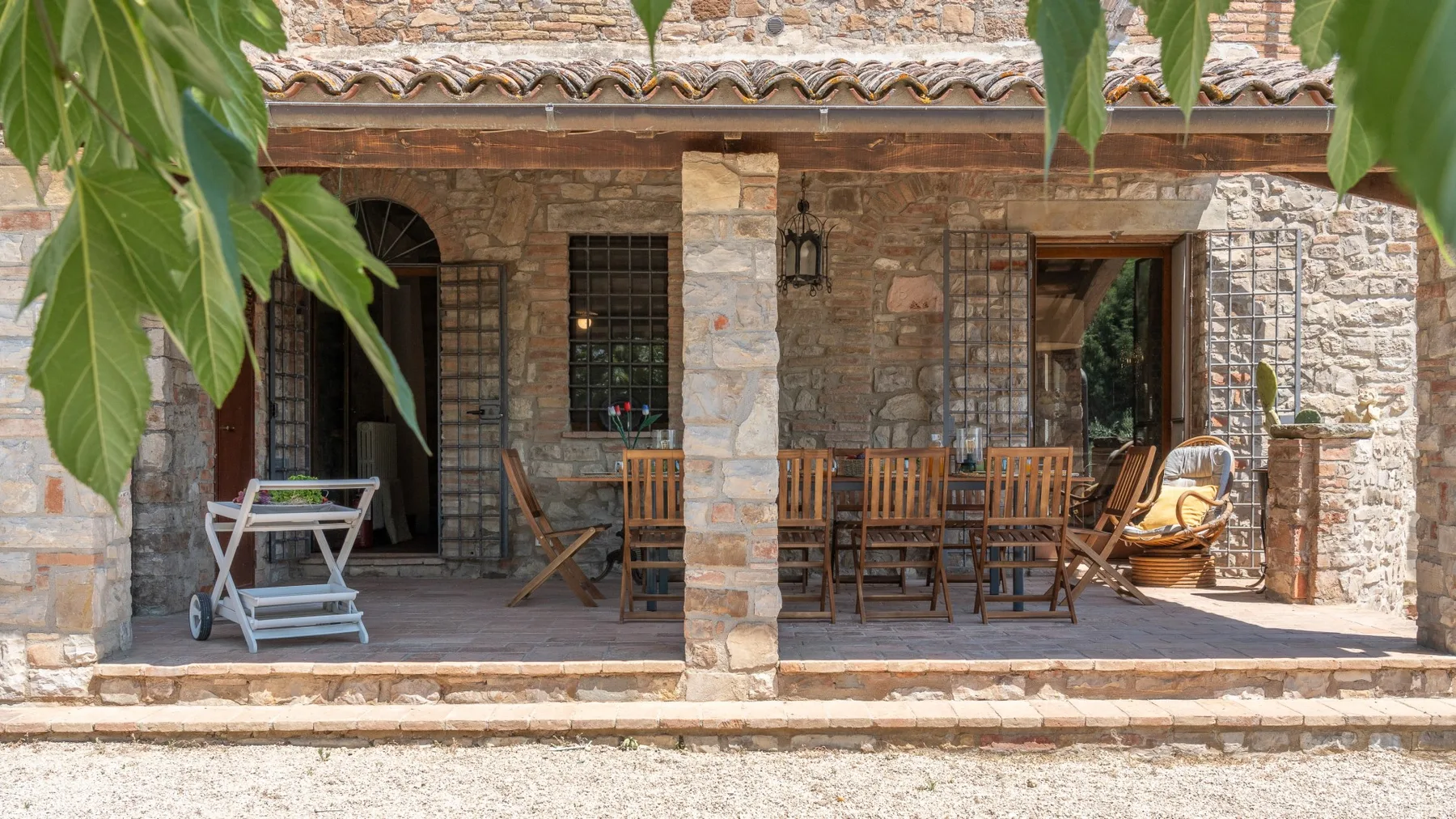 A stone patio with wooden seating and a shaded covered area.