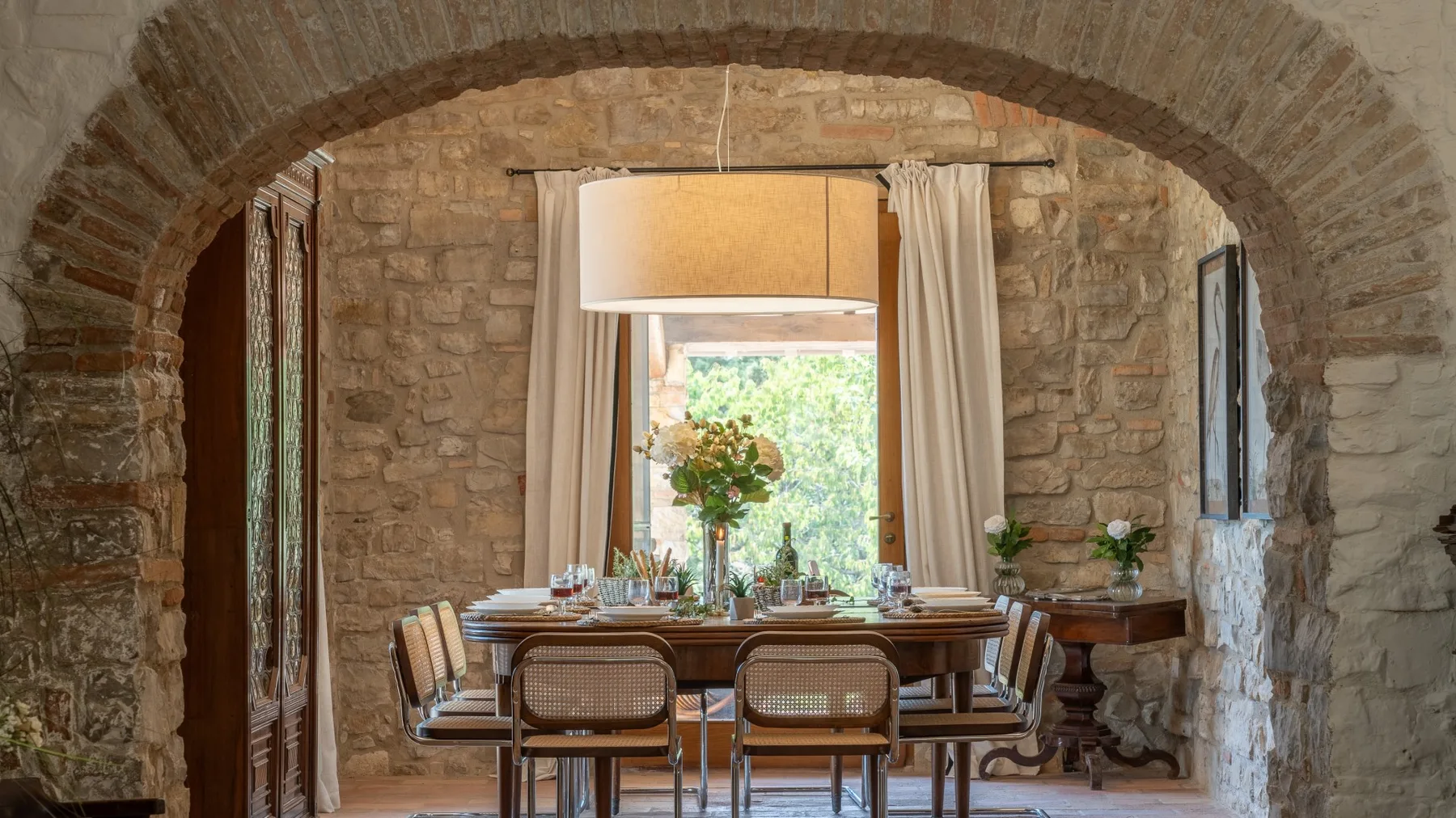 A dining area with a table set beneath a broad stone arch.