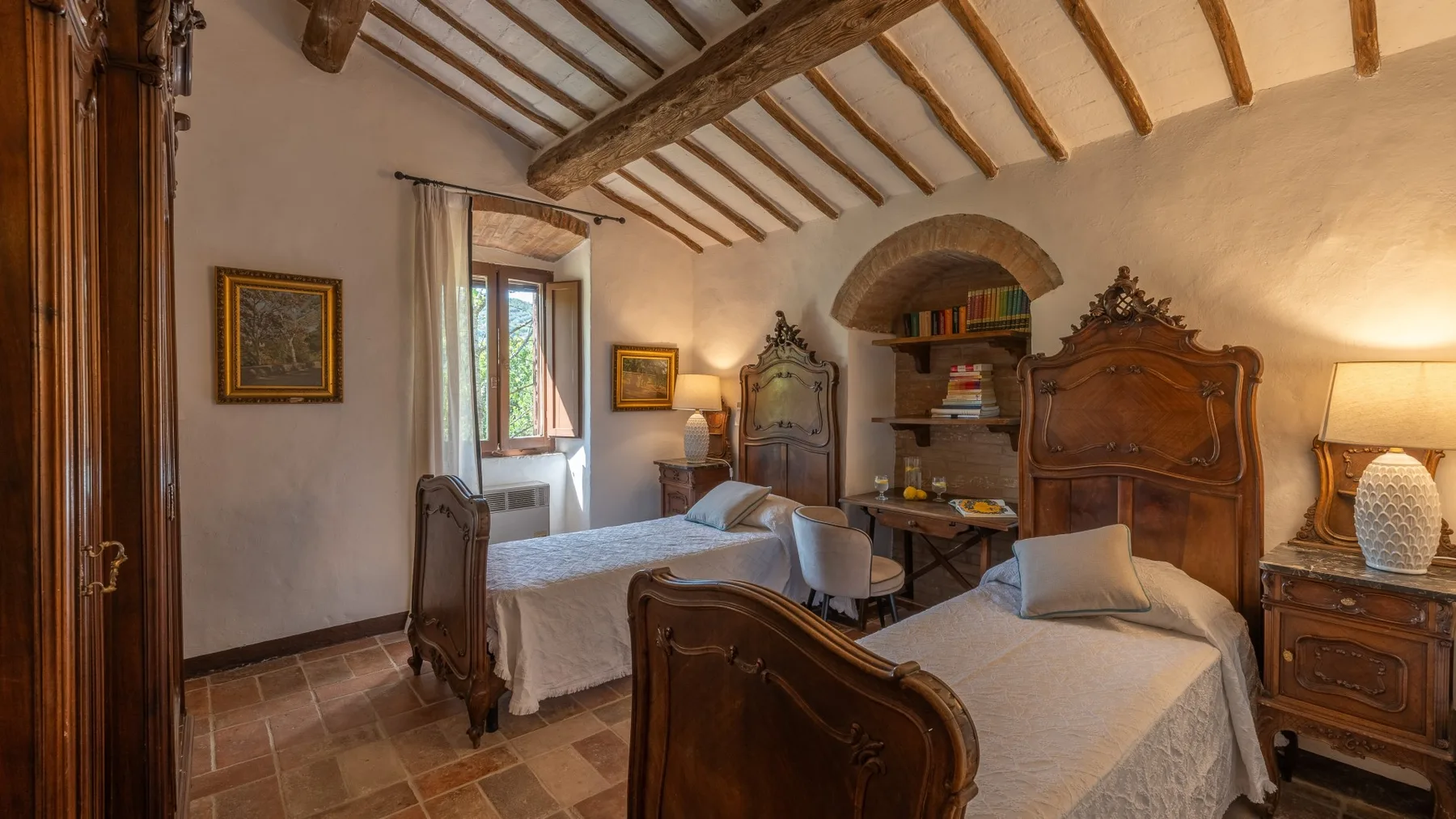 A bedroom with two beds and exposed wooden ceiling beams.