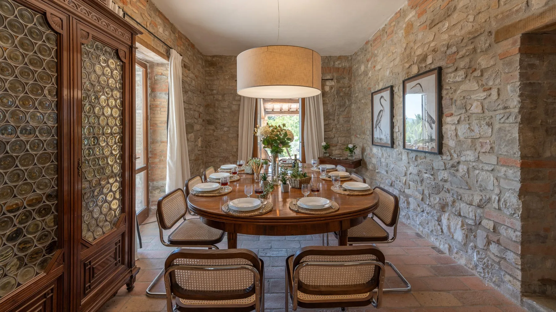 A dining room with a wooden table, chairs, and exposed stone walls.