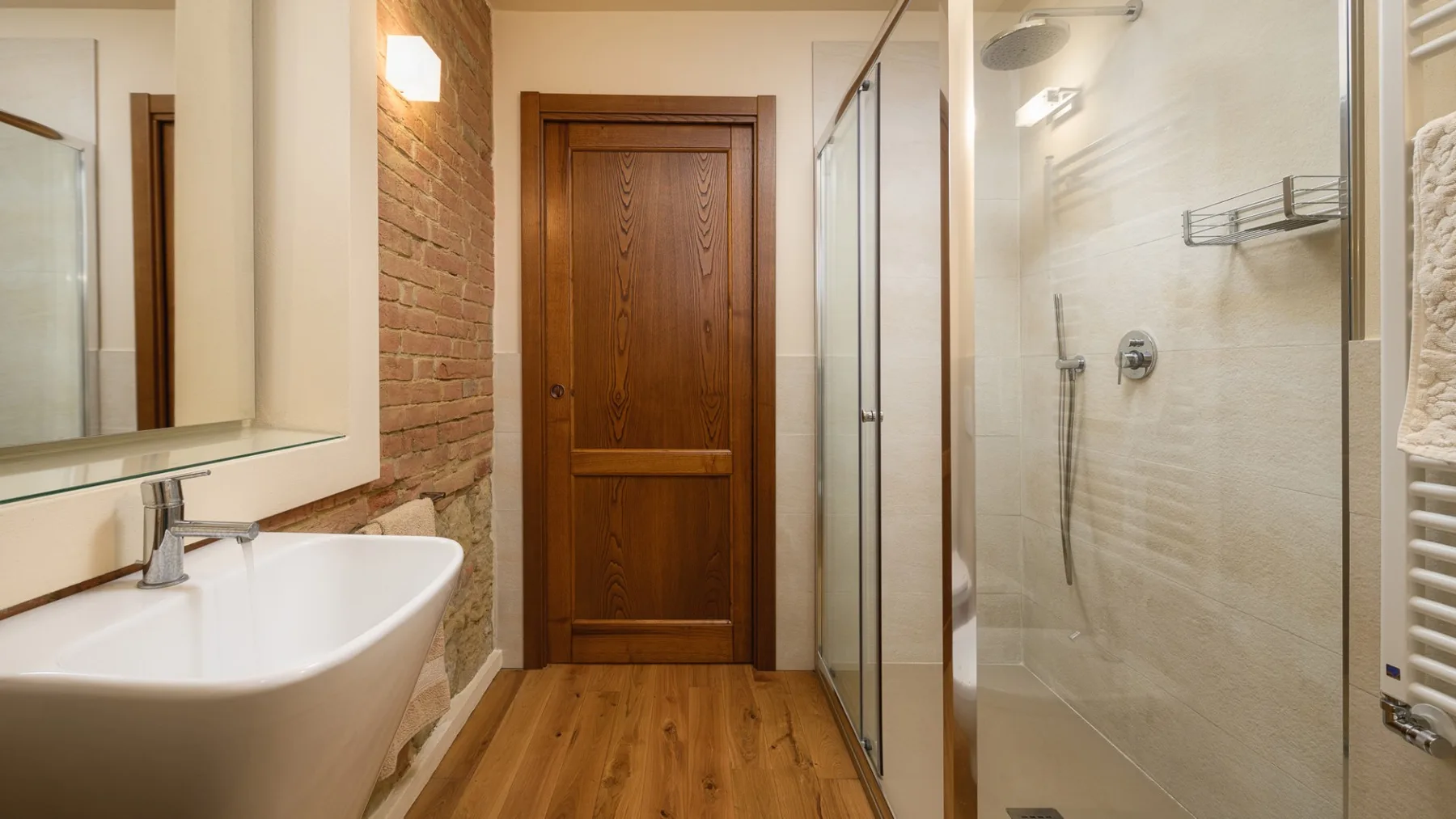 Un baño con lavabo, ducha de cristal y puerta de madera.