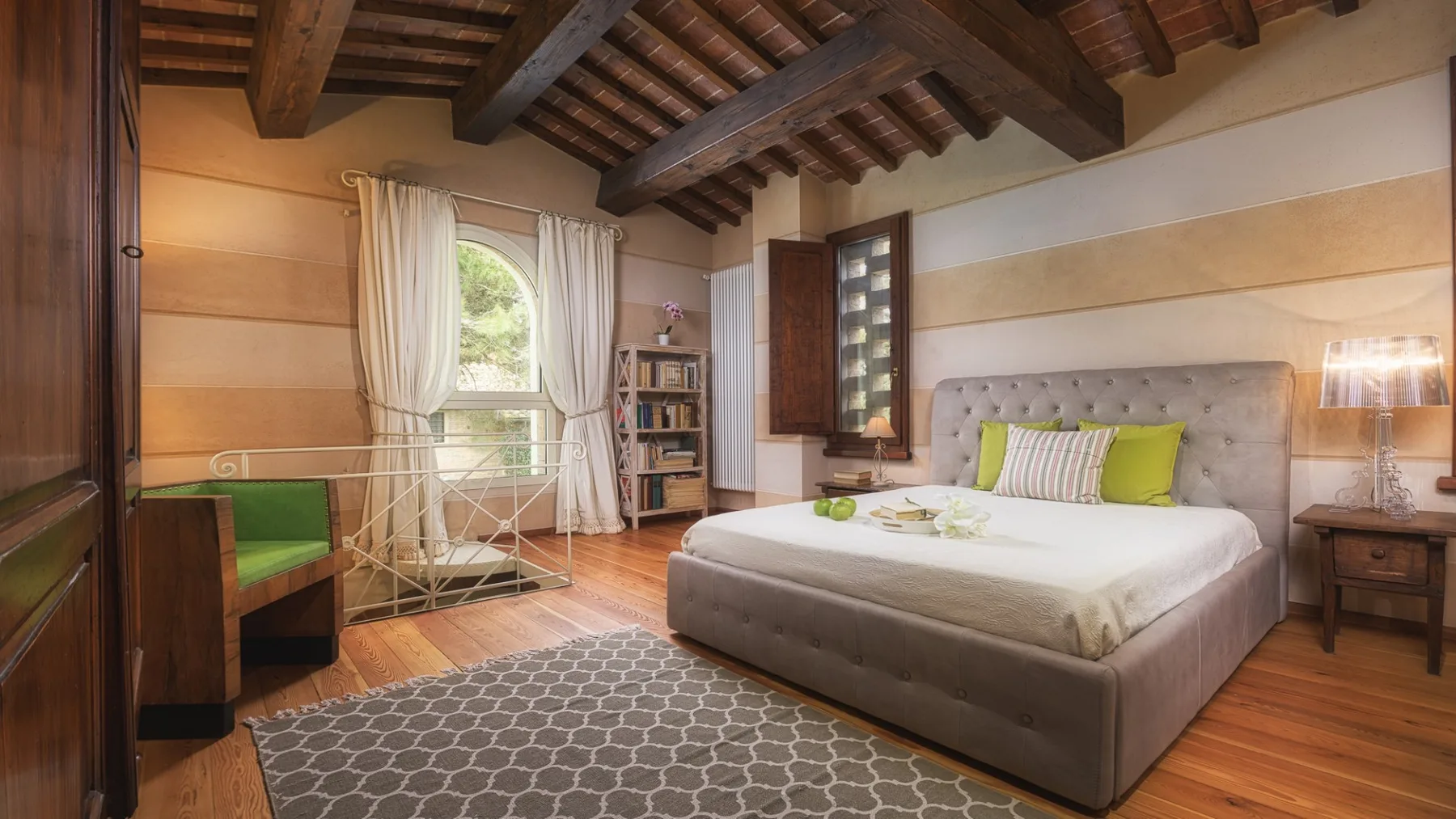 Un dormitorio con una cama grande, una ventana con cortinas y vigas de madera expuestas en el techo.