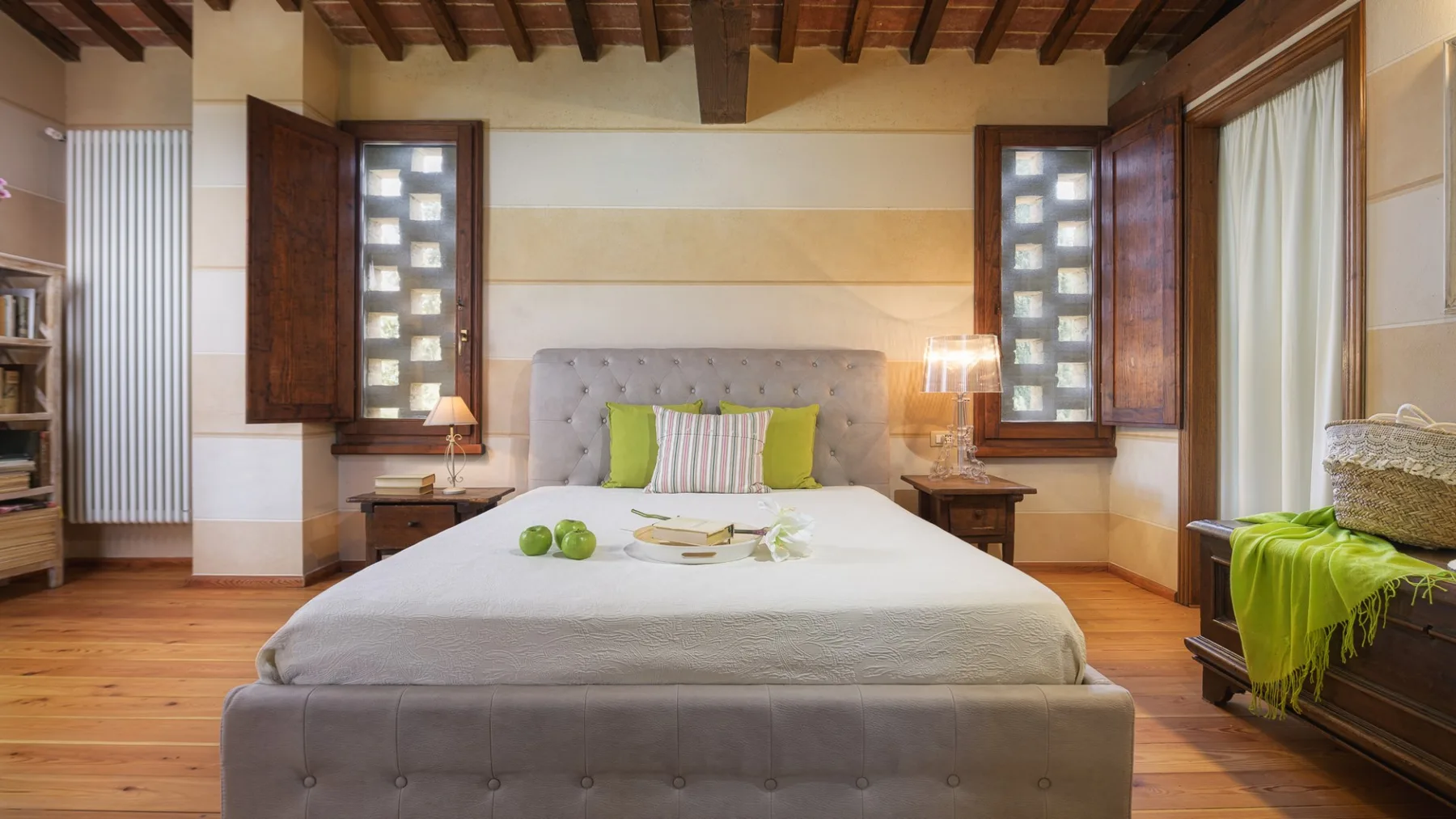 Un dormitorio con una cama, mesitas de noche y vigas de madera en el techo.