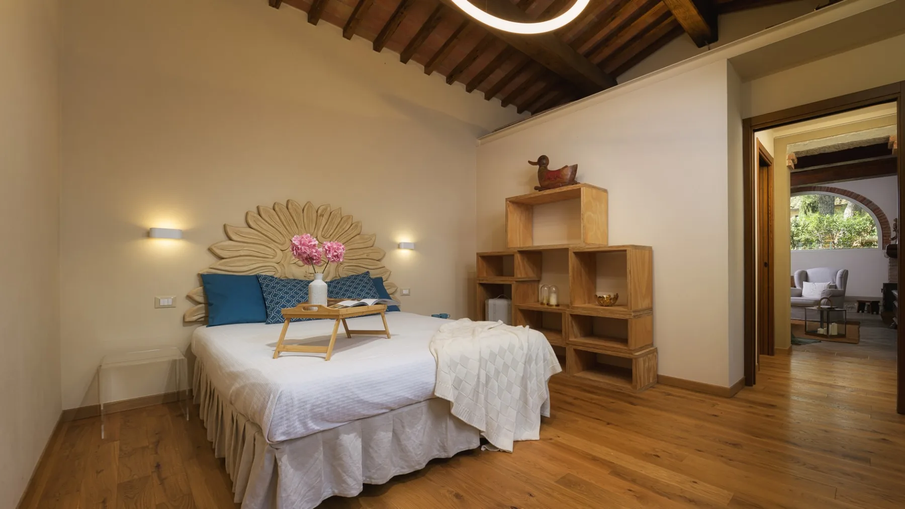 Un dormitorio con una cama, estanterías de madera y vigas expuestas en el techo.