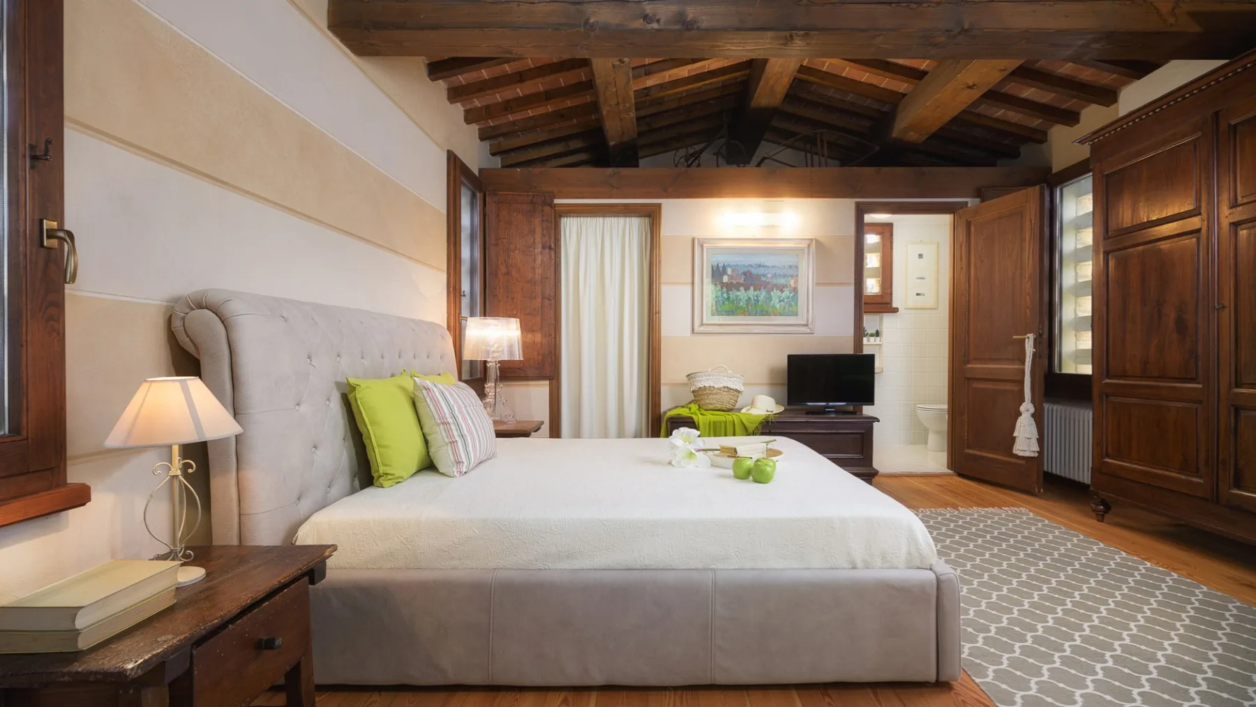 Un dormitorio con una cama grande, vigas de madera a la vista y armarios empotrados.