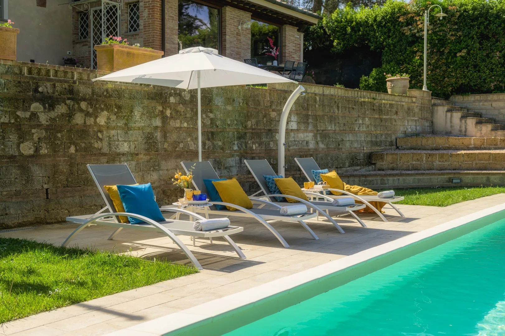 Una piscina junto a asientos reclinables y una gran sombrilla de patio.