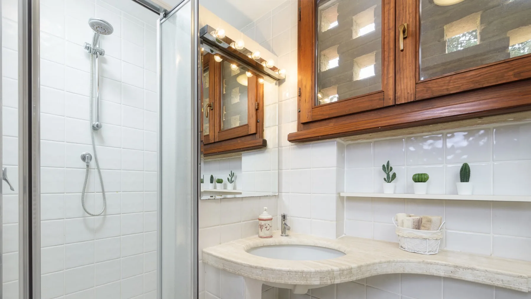Un baño luminoso con una ducha de vidrio y un lavabo curvo.