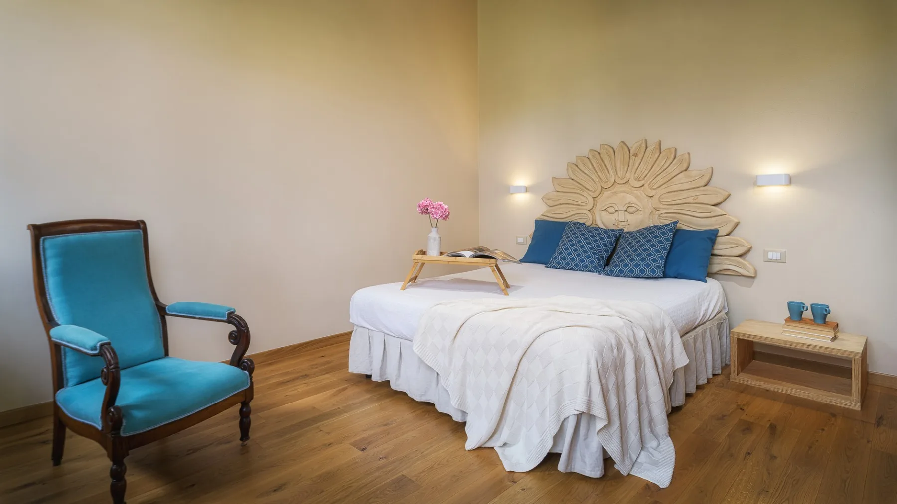 Un dormitorio con una cama, un sillón tapizado y suelo de madera.