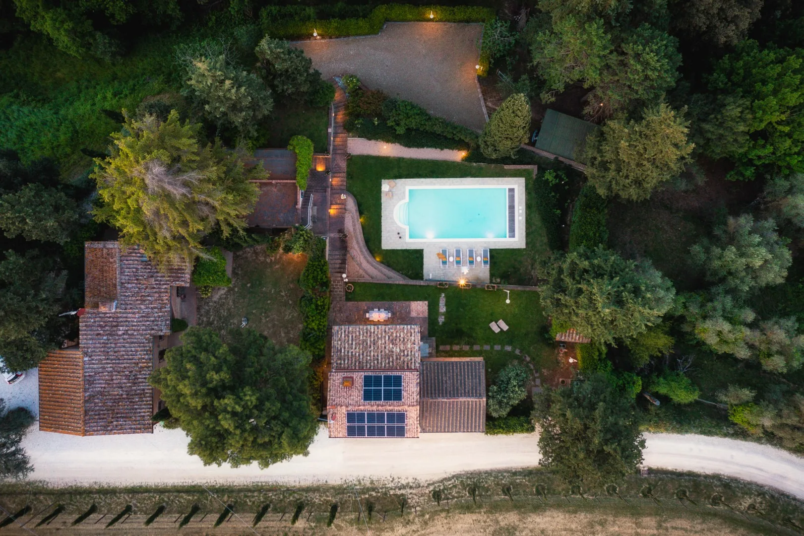 Una vista aérea muestra una piscina, vegetación alrededor y edificios cercanos.